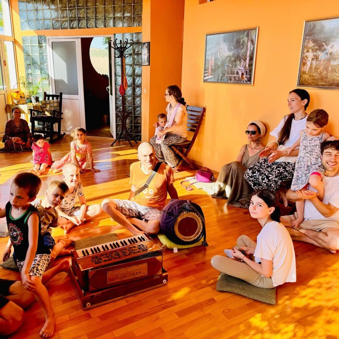 Kīrtan in the temple room — families, children and harmonium together
