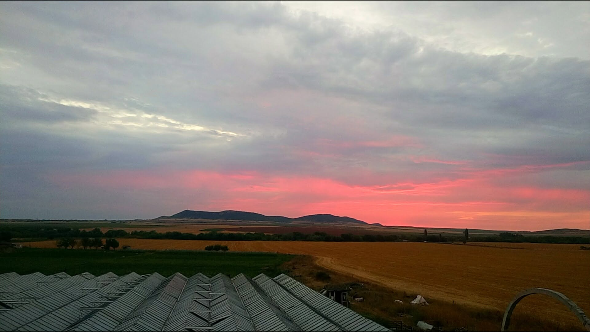 Crimson sunset over the fields — evening returns to the farm