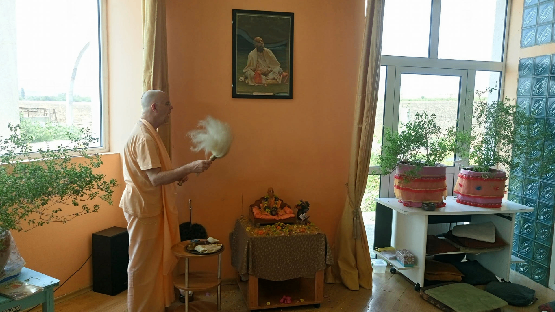 Ārati before Śrīla Prabhupāda — offering the cāmara with fields beyond the window