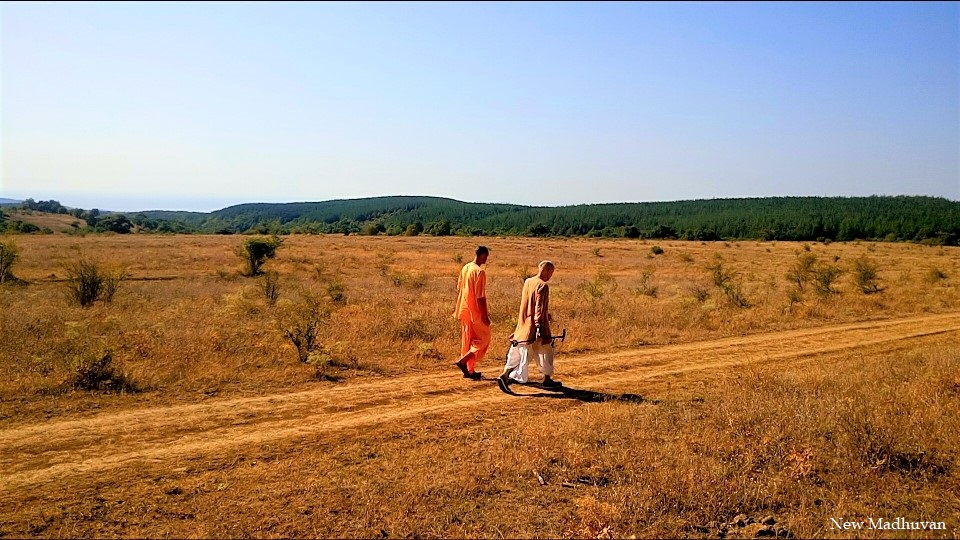 Two devotees walking through the open fields
